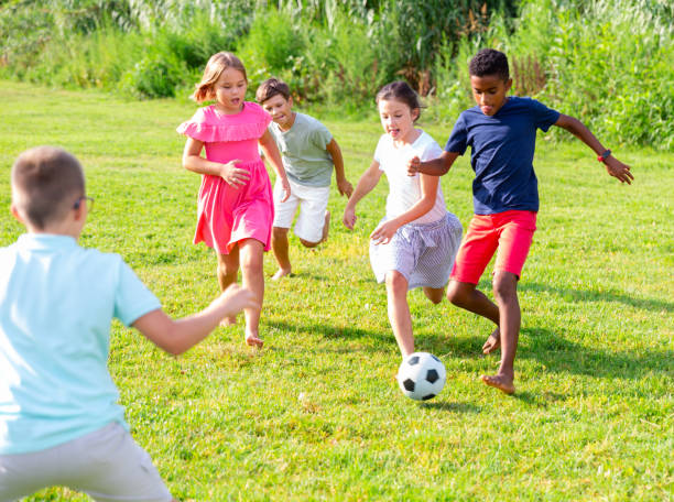 Group of kids playing football on grass stock photo