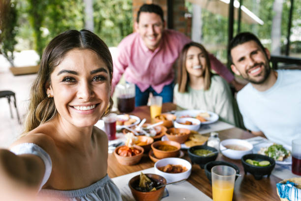 Group of latin friends taking a photo selfie and eating mexican food in the restaurant terrace in Mexico Latin America stock photo
