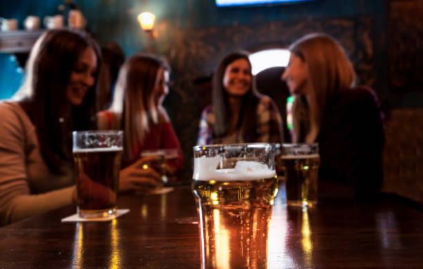 group of millennial women group of millennial women having fun drinking beer in a pub irish women stock pictures, royalty-free photos & images