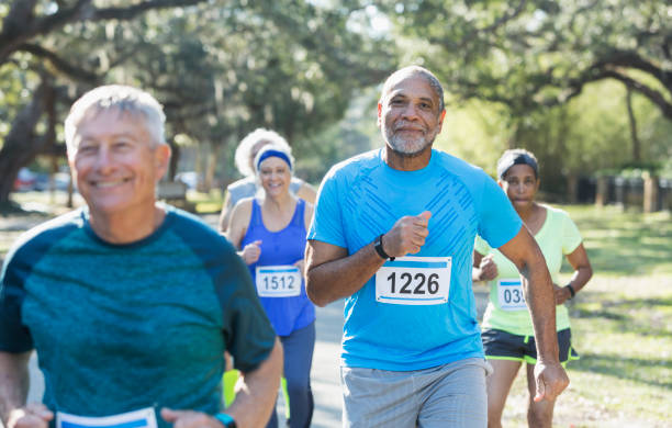 Group of multi-ethnic seniors running a race A group of five multi-ethnic seniors running in a race, wearing marathon bibs. The focus is on the African-American man in the middle foreground. marathon stock pictures, royalty-free photos & images