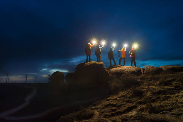 A group of night sky photographers stand on the stone with lamp at night stock photo
