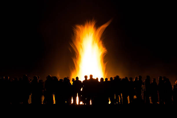 group of people at bonfire Long exposure of people watching a bonfire at night, slight motion blur to people and the fire bonfire stock pictures, royalty-free photos & images