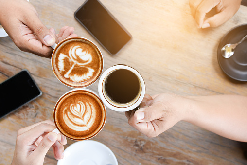 Group of people having a meeting after successful business negotiation in a coffee shop.Drinking hot beverage latte art coffee