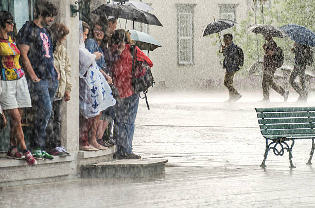 Group of people hide from heavy rain under a building. stock photo