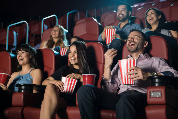 Group of people laughing at the movie theater Small audience of people laughing at the movie theater while watching a comedy and having a good time movie theater stock pictures, royalty-free photos & images