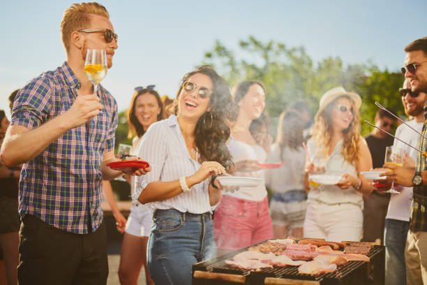 Group of people standing around grill. stock photo
