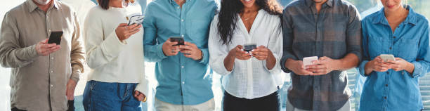 Group of people using mobile devices with a mixture of mobile phones and digital tablets. stock photo