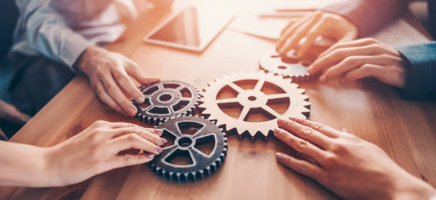 Group of people working in the office while putting together cogwheels. stock photo