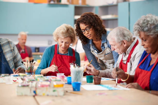 Group Of Retired Seniors Attending Art Class In Community Centre With...
