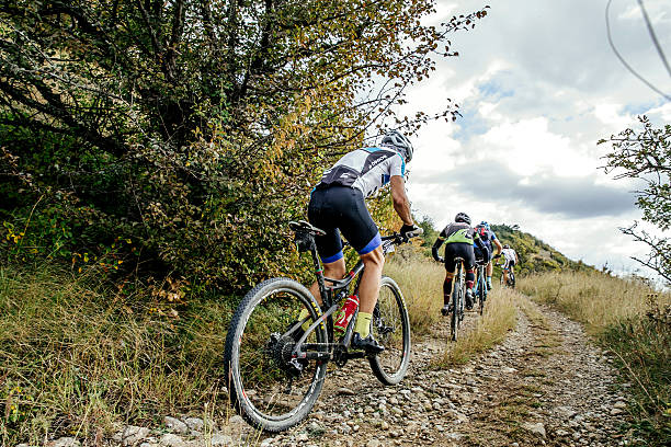 group of riders cyclists riding uphill one behind other stock photo