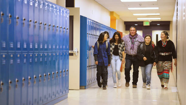 A group of school kids walking with their professor through school corridor stock photo