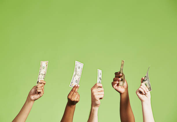 Group of several diverse hands holding up US dollar banknotes of different denominations stock photo