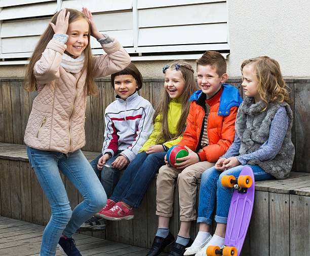 Group of smiling children playing charades Group of smiling children sitting on bench and playing charades together charades stock pictures, royalty-free photos & images