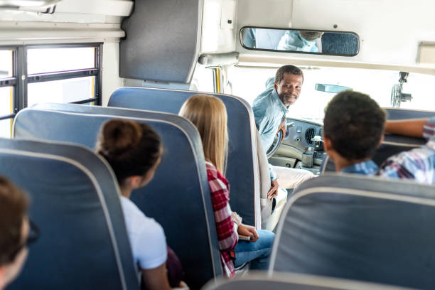 group of teen scholars riding school bus and talking with happy mature driver  school bus driver stock pictures, royalty-free photos & images