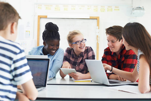 Group Of Teenage Students Collaborating On Project In IT Class stock photo