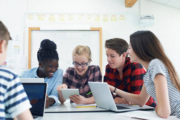 Group Of Teenage Students Collaborating On Project In IT Class stock photo