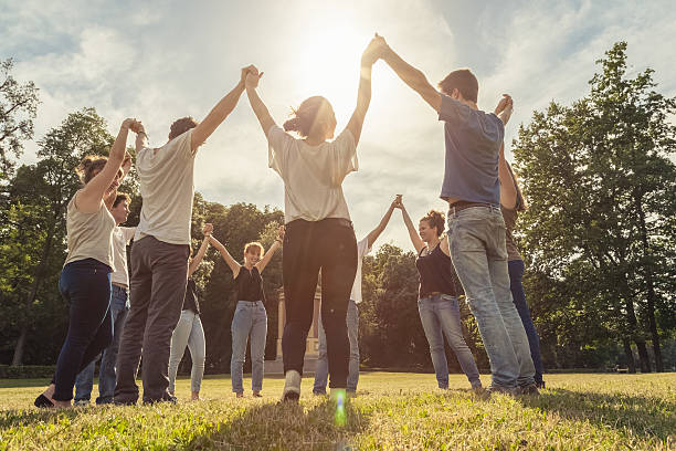 Group of ten friends at the park holding hands stock photo