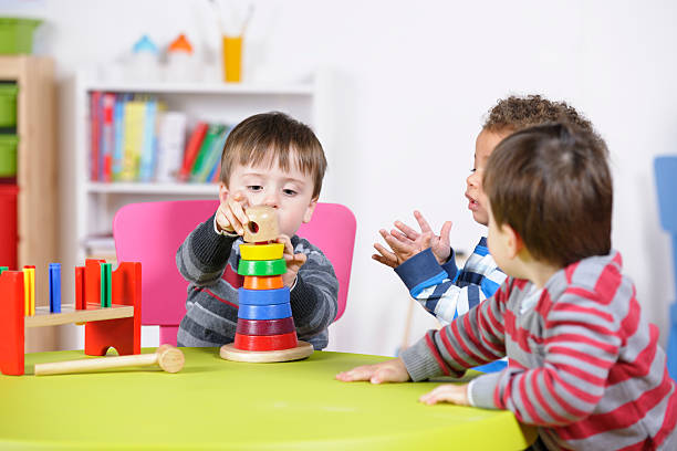 Group of toddlers playing with develpomental toys in a nursery setting.