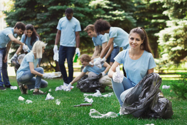 Group of volunteers with garbage bags cleaning park Save the planet. Happy woman volunteer cleaning park with friends, copy space event cleaning stock pictures, royalty-free photos & images