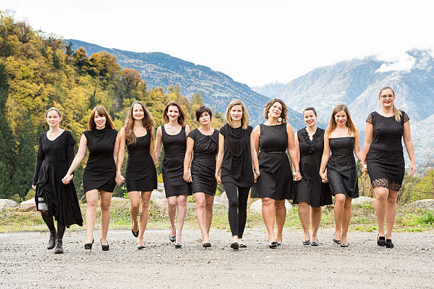 Group of women in black dress walking hand in hand stock photo