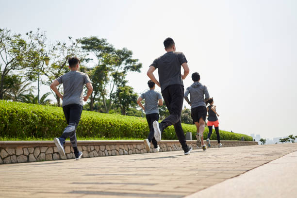 group of young asian adults running in public park stock photo
