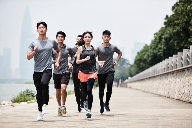 group of young asian adults running outdoors stock photo