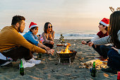 ビーチでクリスマスパーティーを楽しんだり、マシュマロを食べたりする若い友達のグループ