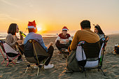 ビーチでクリスマスパーティーを楽しんだり、マシュマロを食べたりする若い友達のグループ