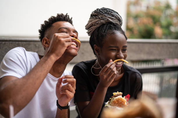 groupe de jeunes s’amuser dans un restaurant - eating burger photos et images de collection