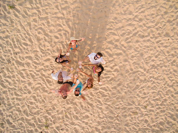 group of young people making selfie with drone at beach - man,standing, elevated view,remote control stockfoto's en -beelden