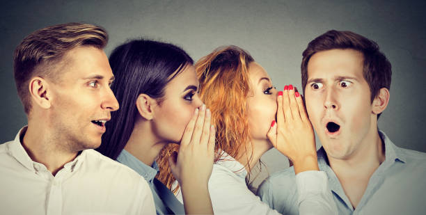 Group of young people men and women whispering each other in the ear stock photo