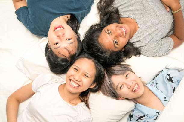 Group of young women lying in bed, happy and smiling, top view. stock photo