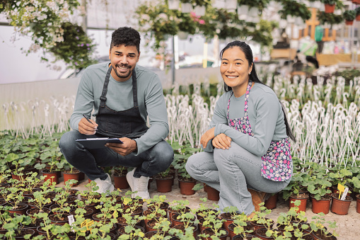 Young Multicultural Couple in Their Greenhouse, Looking at Camera