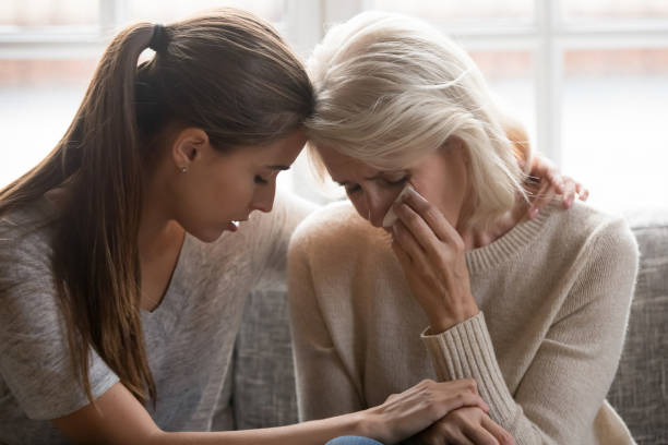 Grownup daughter soothe aged mother holds her hand feeling empathy Grown up daughter soothe aged mother holds her hand feel empathy give her moral support elderly woman crying wipe tears with tissue, health problem disease, divorce broken heart adult child supporting grief stock pictures, royalty-free photos & images