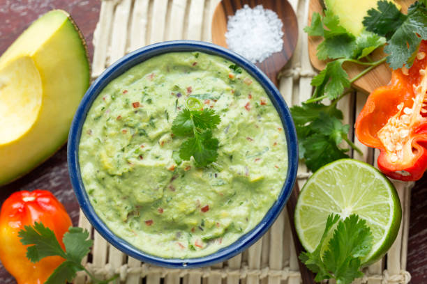 Guacamole Guacamole surrounded by its ingredient. Dip made of avocado, chili or sweet pepper, lime, cilantro and salt. Healthy  eating. Mexican food. Tex-Mex food. Still life. Horizontal composition photography. Top view. guacamole stock pictures, royalty-free photos & images