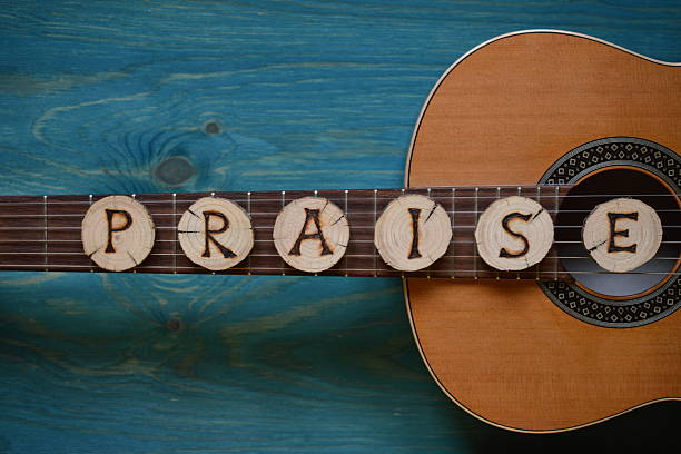 guitar on teal wood and the word: PRAISE stock photo