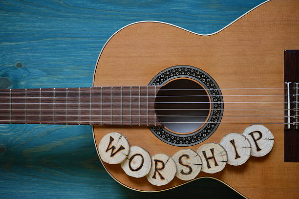 guitar on teal wood and the word WORSHIP stock photo