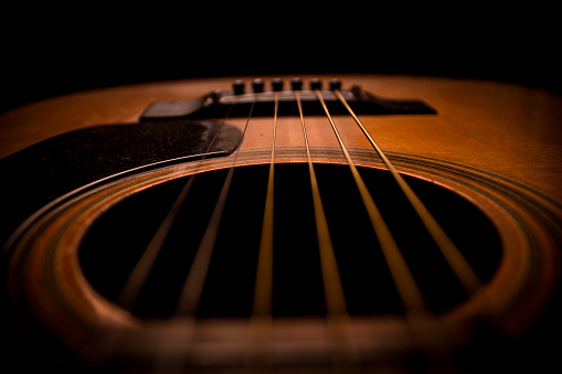 Closeup image of an acoustic guitar's chords in a dark area inside my house.It is a vintage photo.