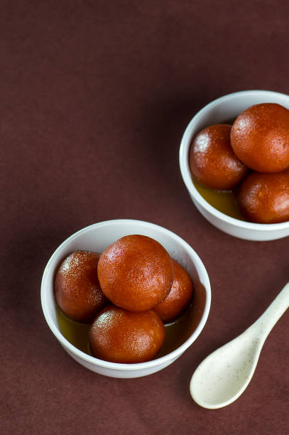 Gulab Jamun, Indian Dessert or Sweet Dish in bowl with spoon stock photo