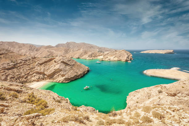 Gulf of Oman Coast Green Lagoon with Small Hidden Beach Oman Beautiful green, blue lagoon with a small hidden beach between the harsh rocky coastal landscape at the Gulf of Oman Rocky Coast. Sultanate of Oman, Middle East oman stock pictures, royalty-free photos & images