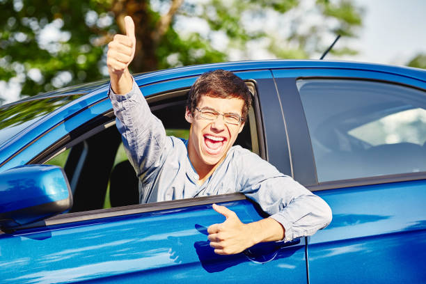 Guy inside car showing thumbs up Close up of young hispanic man wearing glasses showing thumb up hand gesture and happy screaming through car window - driving school and new drivers concept passed driving test stock pictures, royalty-free photos & images