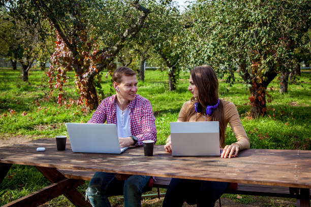 A guy with a girl working on laptops in the park stock photo