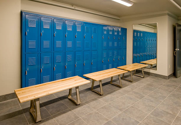 Gym locker room with wooden benches and blue lockers stock photo