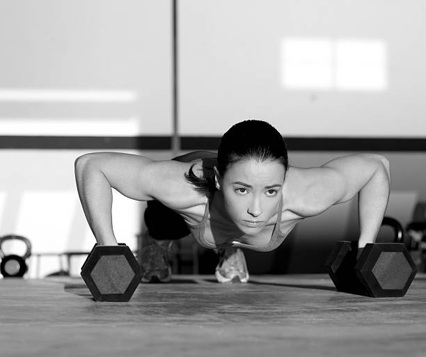 Gym woman push-up strength pushup with dumbbell Gym woman push-up strength pushup exercise with dumbbell in a gym workout hex dumbbells stock pictures, royalty-free photos & images