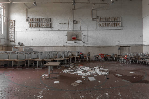 Gymnasium with stacked desks in abandoned high school stock photo