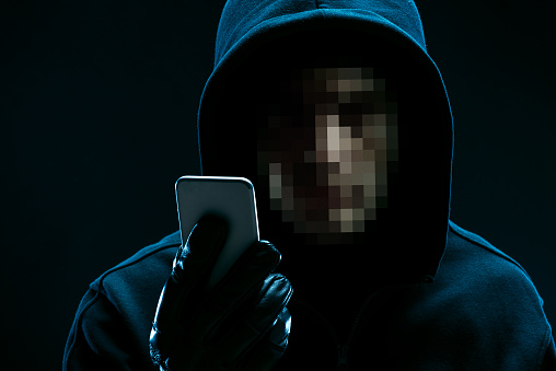 Portrait of unrecognizable hacker with smartphone