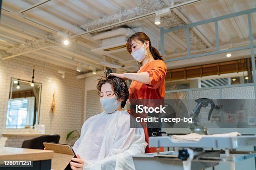 istock Hair dresser drying costumer's hair. Owner and customer wearing protective face mask for illness prevention 1280171251