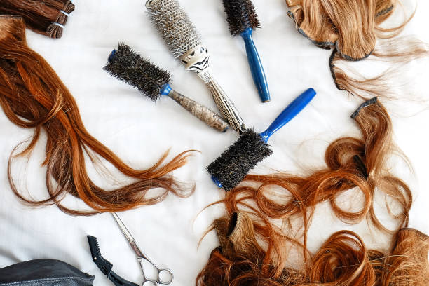 Hairbrushes and false hair with scissors. stock photo