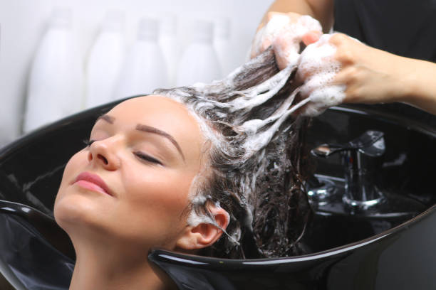 kapper wassen van de haren van de vrouw in de kapsalon - woman washing hair stockfoto's en -beelden