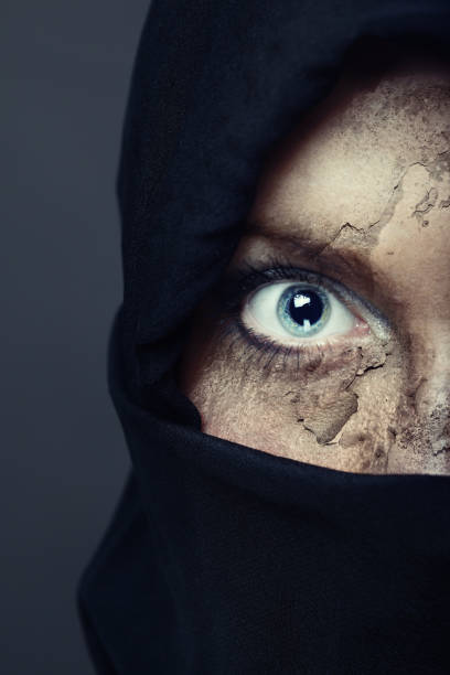 Half face of the human in black hood with damaged skin. Artistic colors and painting added stock photo